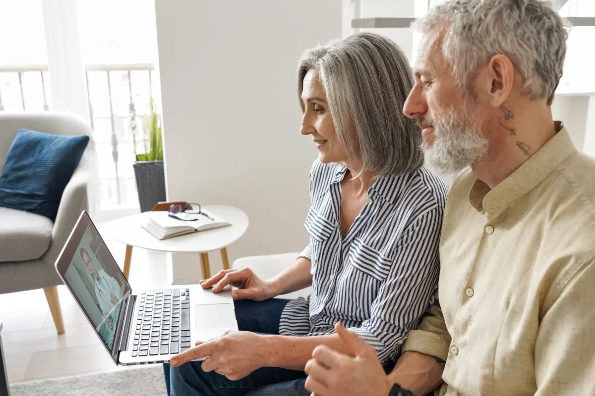 Two people using a laptop to connect with a doctor